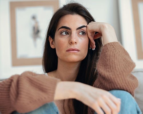 Mujer sentada, con semblante serio, pensativo