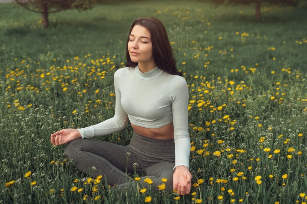 Mujer en pose de meditación, sentada en un campo de flores